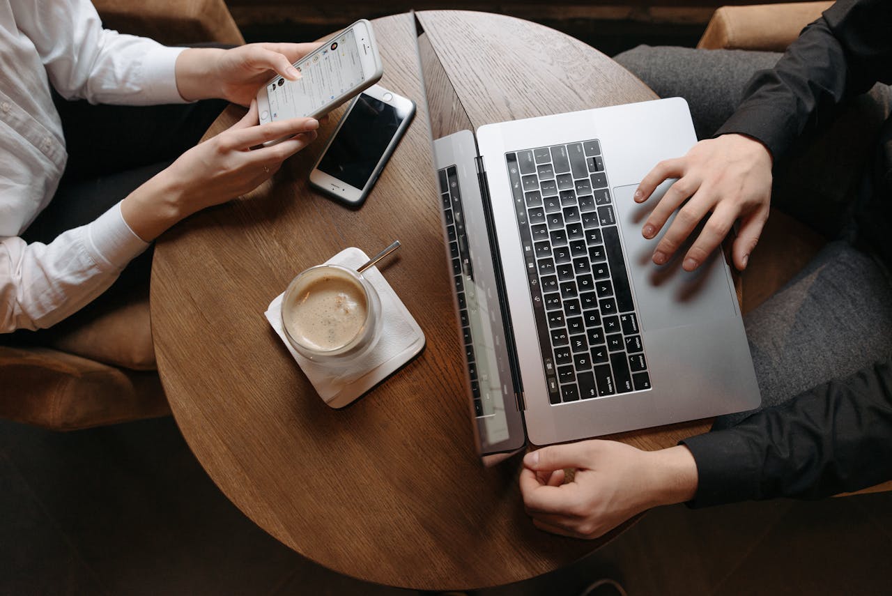 Overhead view of professionals using technology devices at a café table.